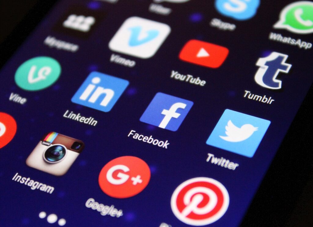 A close-up of a smartphone screen displaying social media app icons, including Instagram, LinkedIn, Facebook, Twitter, Pinterest, Google+, and others.