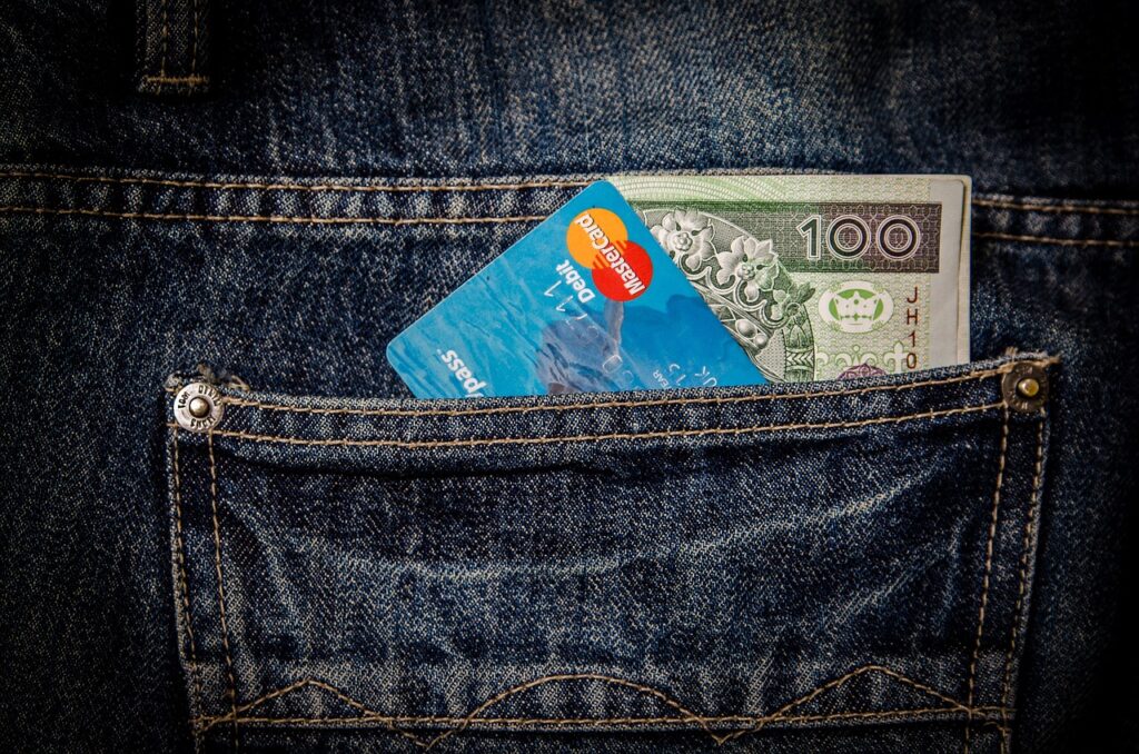 A 100-zloty banknote and a MasterCard credit card are partially visible in the back pocket of blue denim jeans.