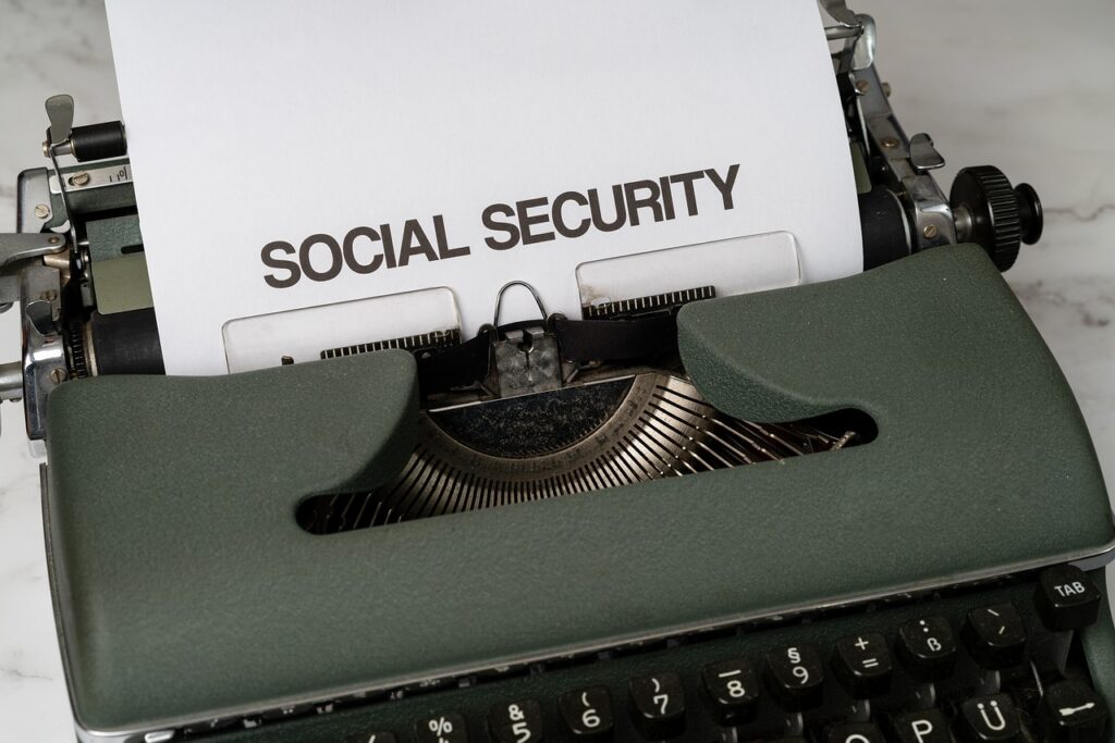 A typewriter with a sheet of paper showing the words "Social Security" emerging from it, positioned on a light-colored surface.